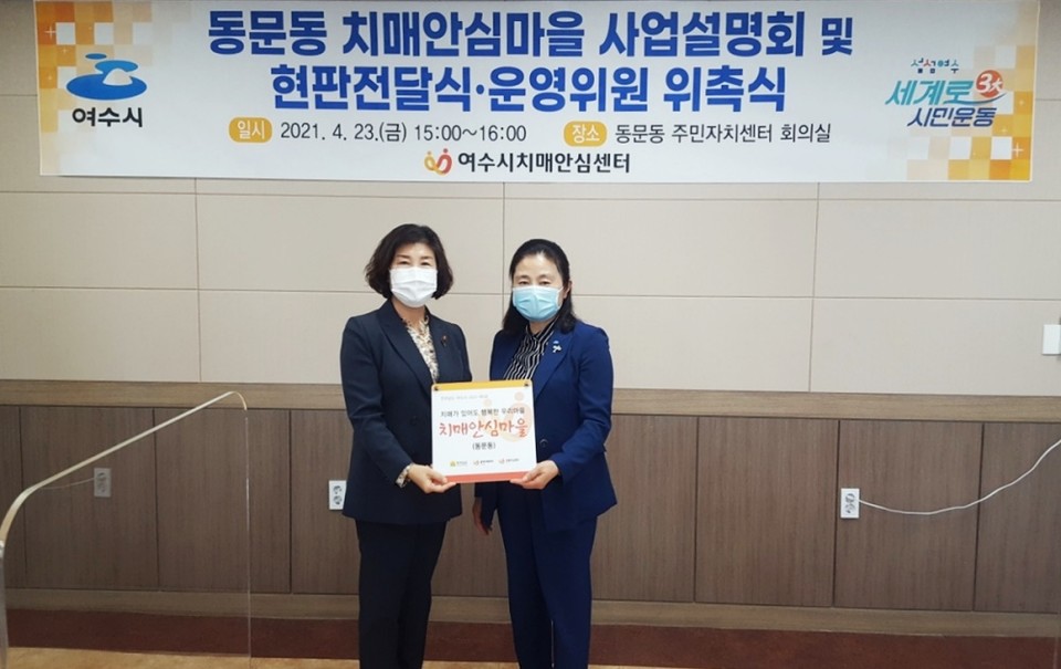 ▲이주리 치매안심센터장이 조영화 동문동장에게 현판을 전달하고 있다