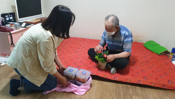 ▲동여수노인복지관 관계자들이 어르신에게 반찬과 카네이션을 전달했다