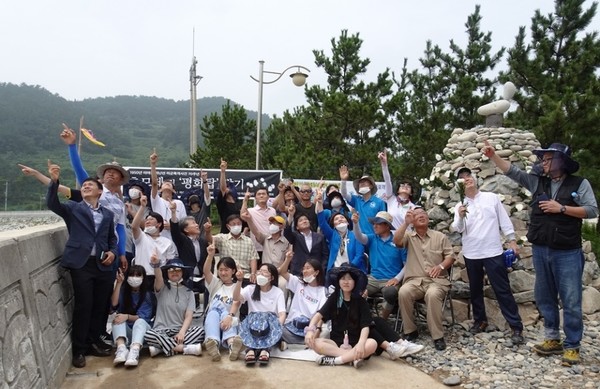 ▲ 2020년 추모제 후 추모탑 앞에서 기념촬영하는 순간  이야포 해변 상공을 갑자기 날아온 수백마리  새떼가 선회하자 참석자들이 새떼를  가리키고 있는 모습