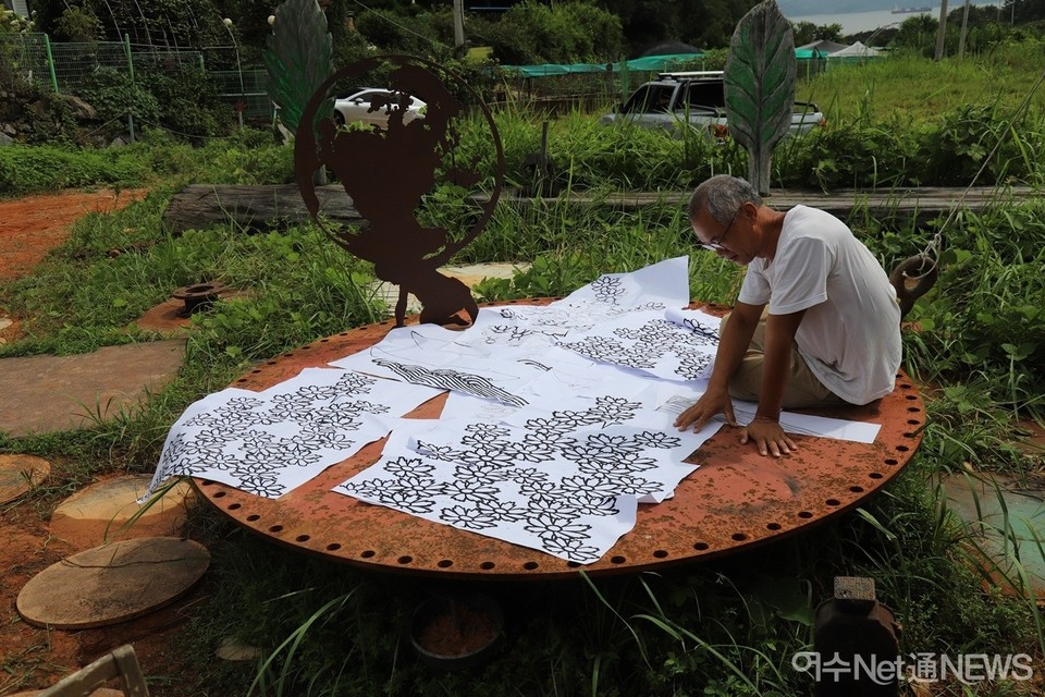 ▲ 최 작가가 돌산 우두리 야외 스튜디오에서 '하늘 꽃' 스케치를 스캔하여 펼쳐보이면서 작업 과정을 설명하고 있다 ⓒ오병종