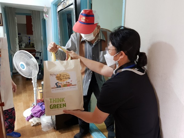 ▲복지관 관계자가 어르신에게 물품을 전달하고 있다