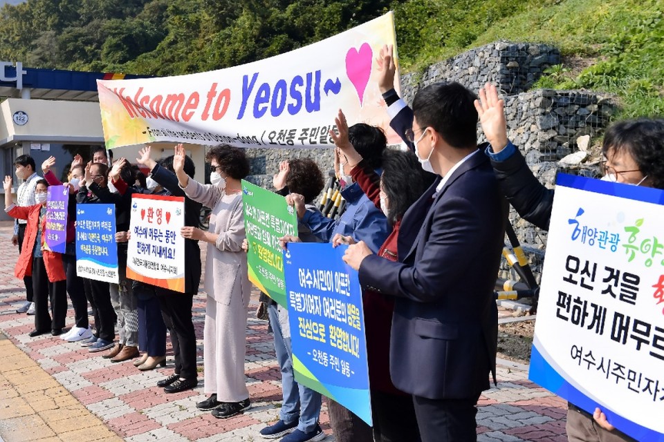 ▲여수해양경찰교육원 앞에서 환영 플래카드와 피켓을 든 여수시 자생단체 회원과 오천동 주민들이 버스 13대에 나눠 타고 여수해양경찰교육원으로 입소하는 아프가니스탄 특별기여자 일행을 향해 따뜻한 환영의 인사를 건네고 있다