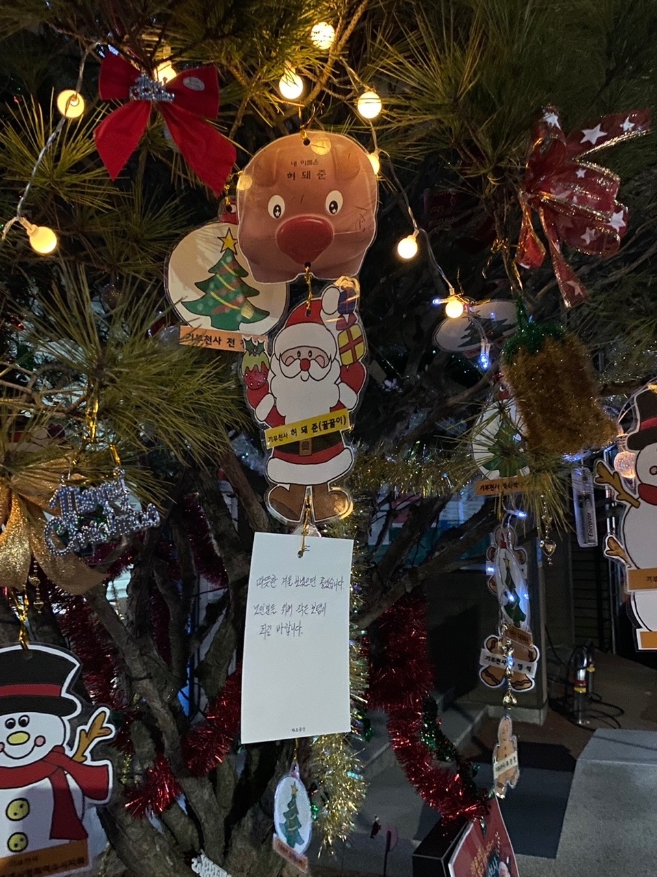 ▲ 여수시 중앙동 기부천사 트리에 익명의 후원자가 기증한 돼지저금통이 손카드와 함께 달렸다.