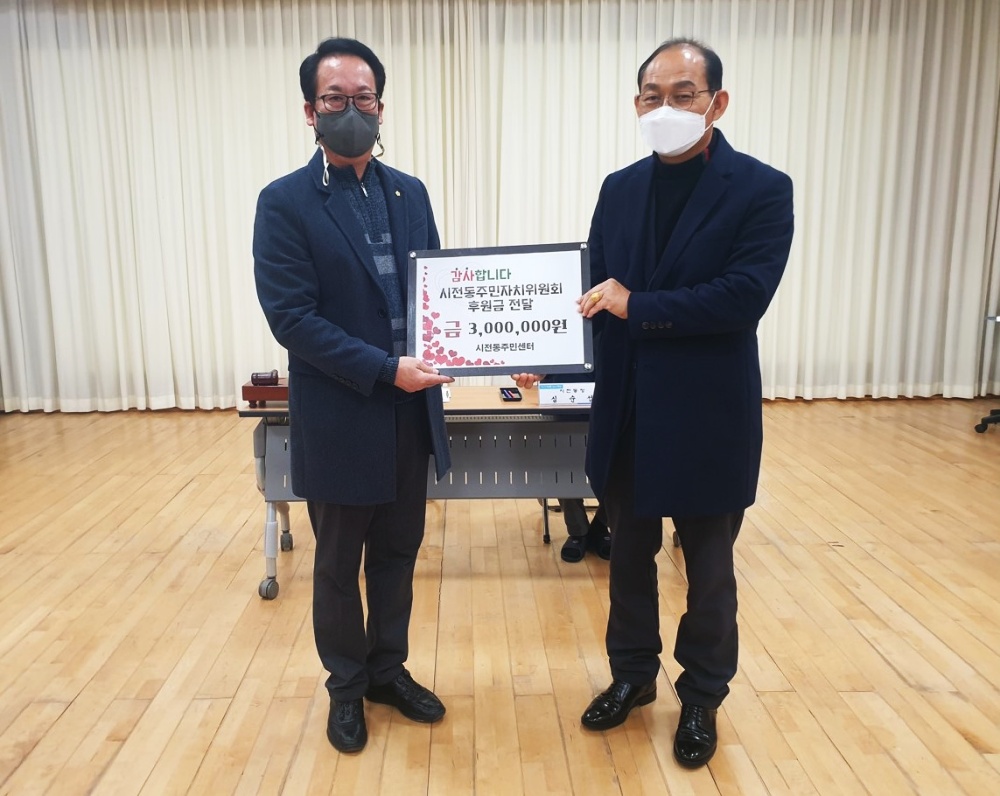▲시전동 주민자치위원회 정창선 위원장이 심순섭 시전동 주민센터장에게 후원금을 전달하고 있다