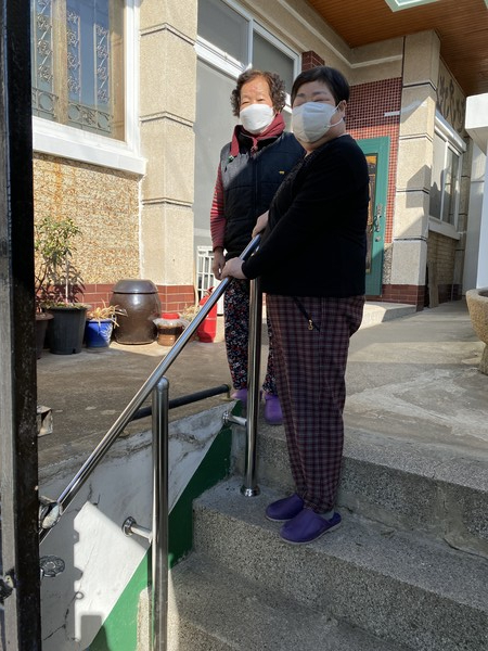 ▲ 재가장애인 박모씨와 어머니 설치된 핸드레일 앞에서 밝은 미소를 짓고 있다