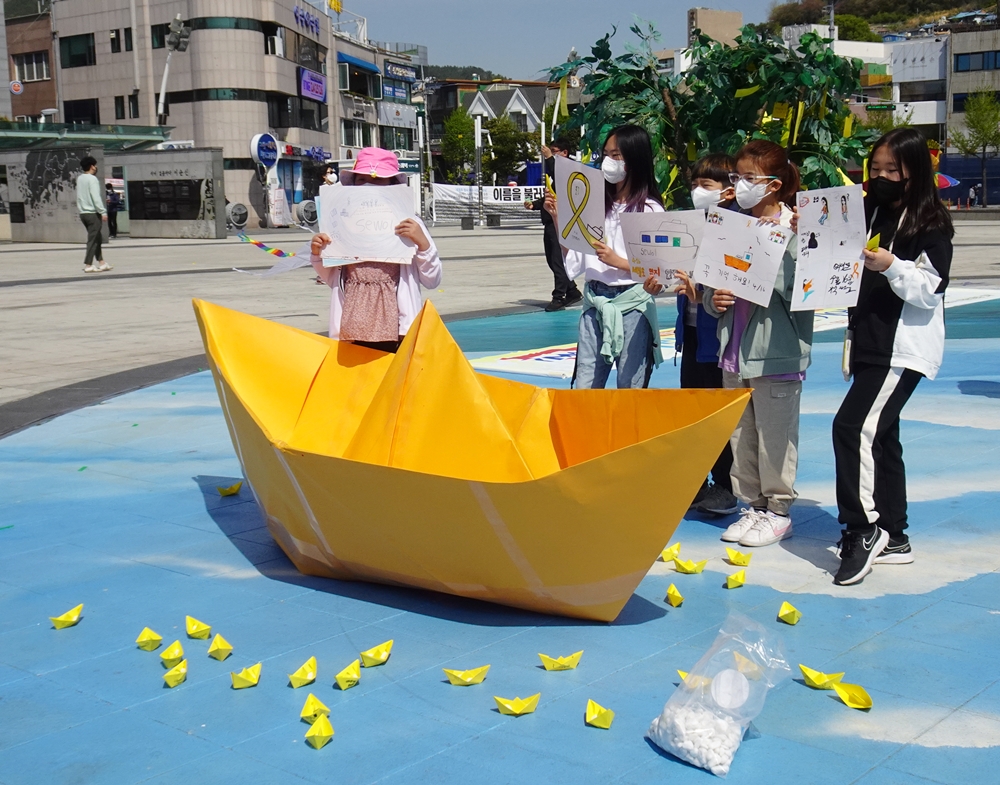 ▲ 모형 종이배 뒤에 선 학생들.