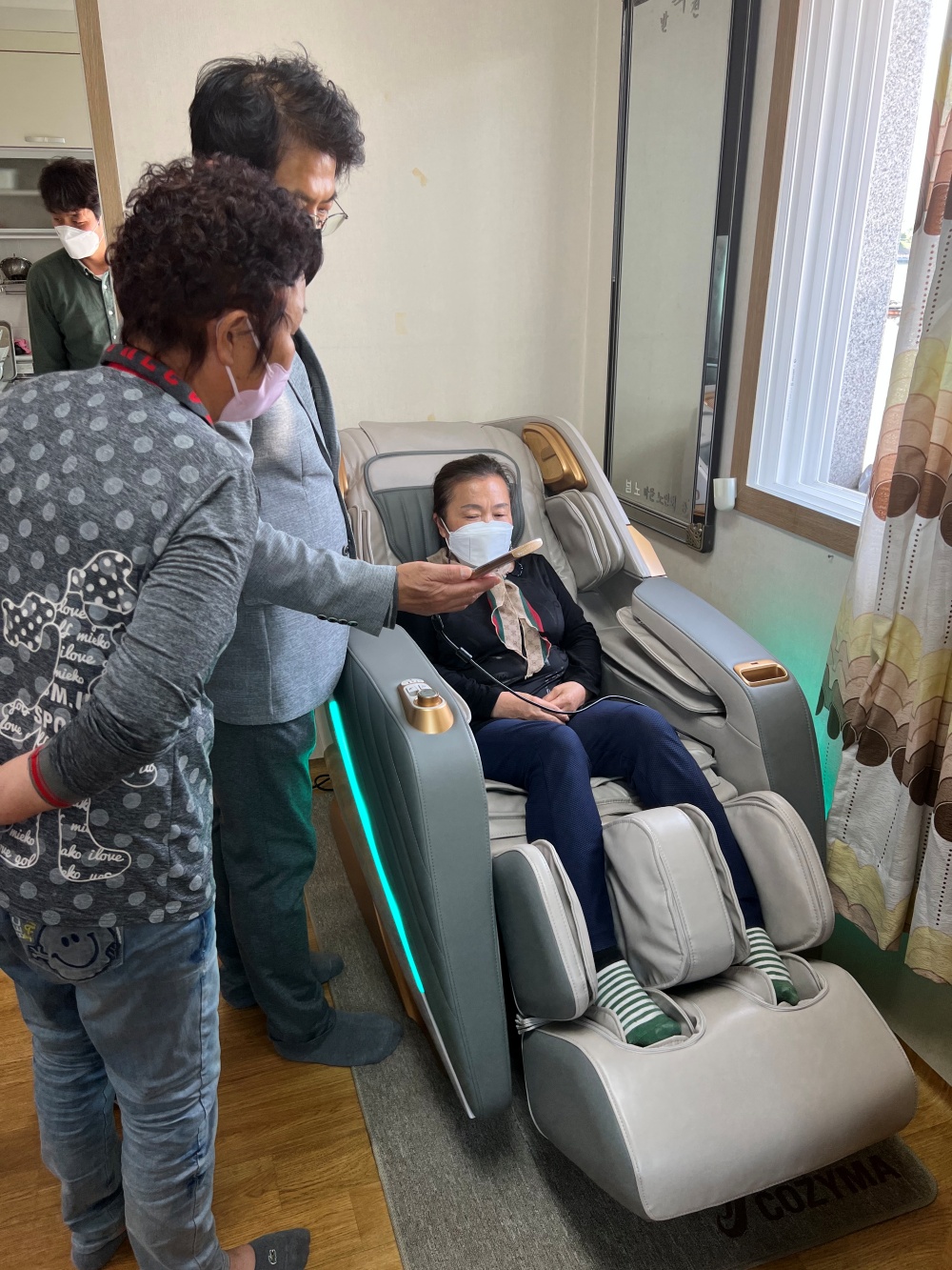 ▲ 어르신이 안마의자 이용방법을 설명듣고 있다.