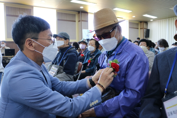 ▲ 여수시노인복지관 김진우 관장이 행사에 참석한 어르신께 카네이션을 달아드리고 있다.