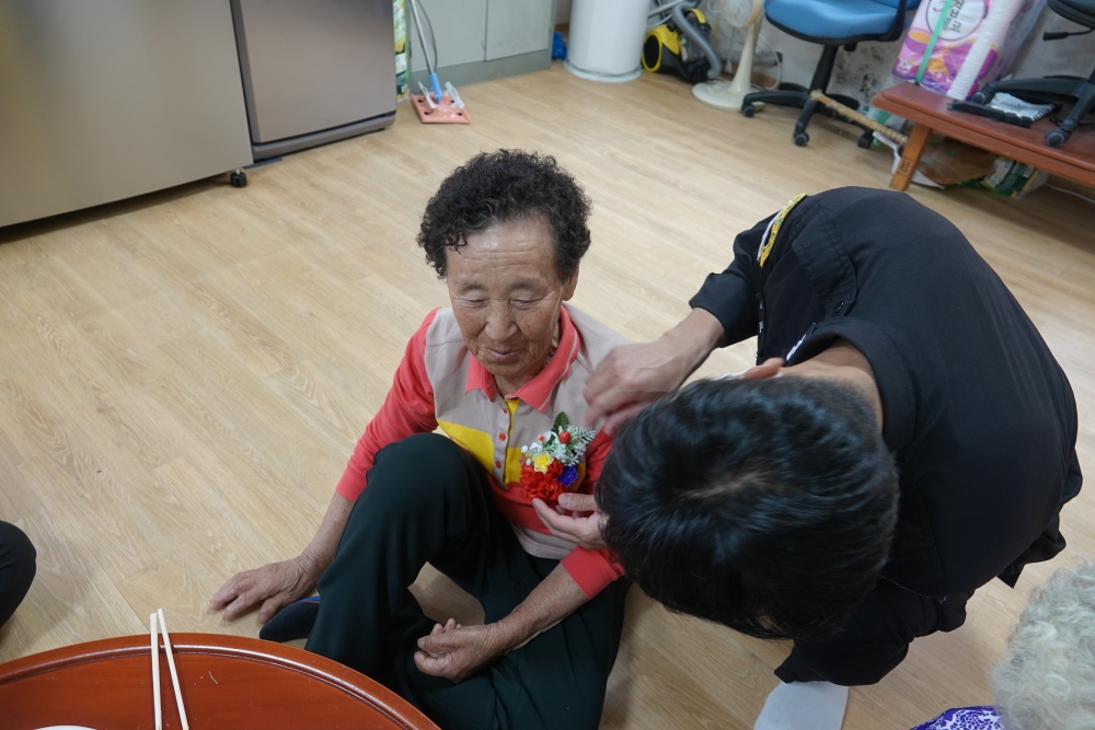 ▲ 가거경비대가 어르신께 꽃을 달아드리고 있다.