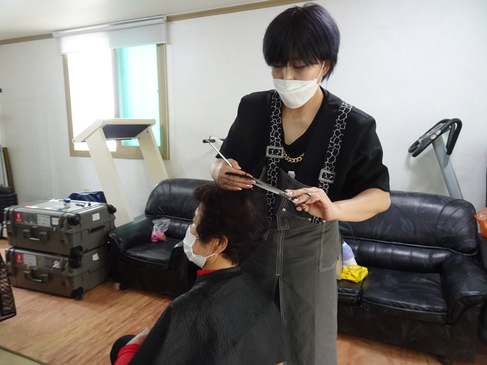 ▲ 삼이뷰티샵 한승연 원장이 어르신의 머리를 잘라드리고 있다.