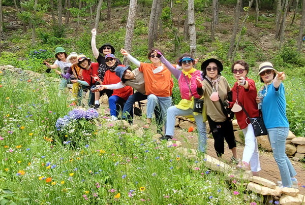 ▲ 자원봉사자들이 수국등 다양한 꽃과 함께 사진을 찍고 있다