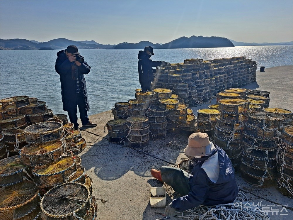 ▲정종현 작가가 달천 바닷가에서 낙지잡이 통발을 보수하고 있는 어부 부부를 촬영하고 있다.  ⓒ조찬현