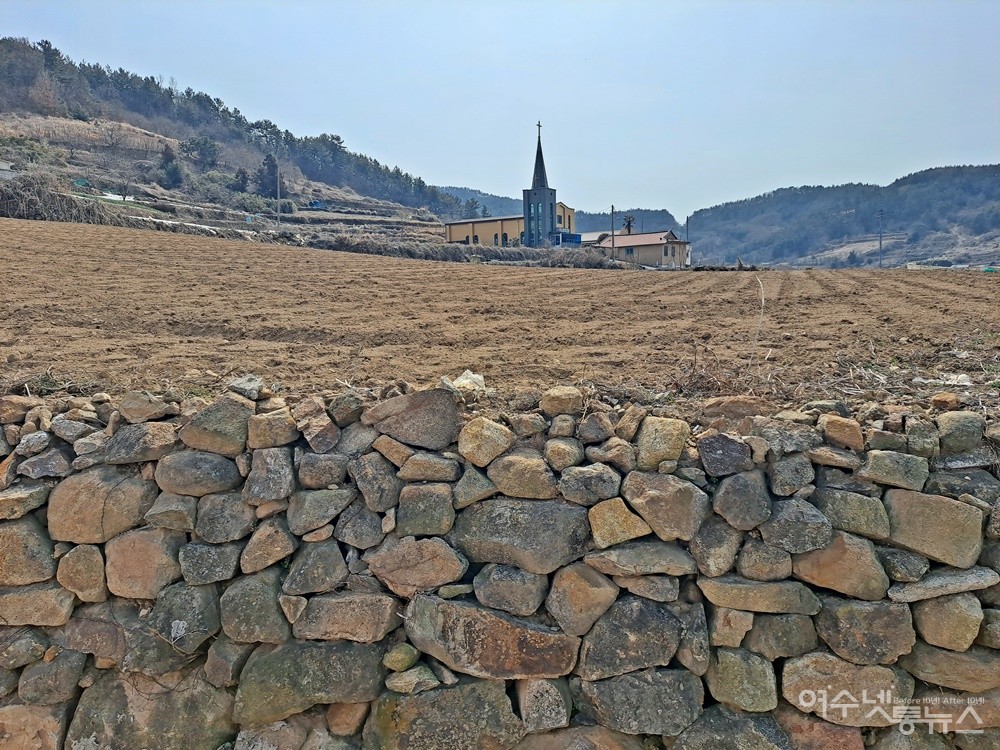 ▲작물을 심기 위해 갈아엎은 텅 빈 밭 너머로 교회가 보인다.  ⓒ조찬현