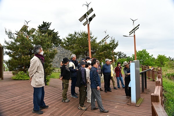 ▲필자가 묘도봉화대 인근에 세워진 안내문에 대해 설명하는 동안 듣고 있는 일행들 모습. 뒤쪽에 정유재란 당시 전황을 전하기 위해 가장 긴박했을 묘도봉화대가 보인다. ⓒ 오문수
