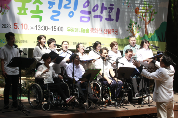 ▲이중현 지휘자와 여수시장애인종합복지관 너울가지 합창단이 무대에서 공연하고 있다.