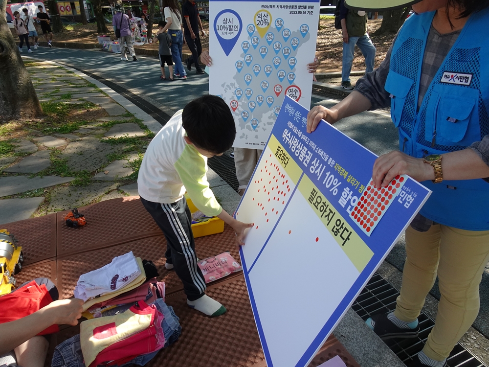 ▲ 거북선공원 벼룩시장에 참여한 아이가 길거리투표 스티커를 붙이고 있다.