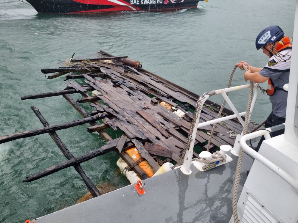 ▲폭우에 폐바지가 표류되어 해양경찰관이 경비함정에 고박조치 하고 있다