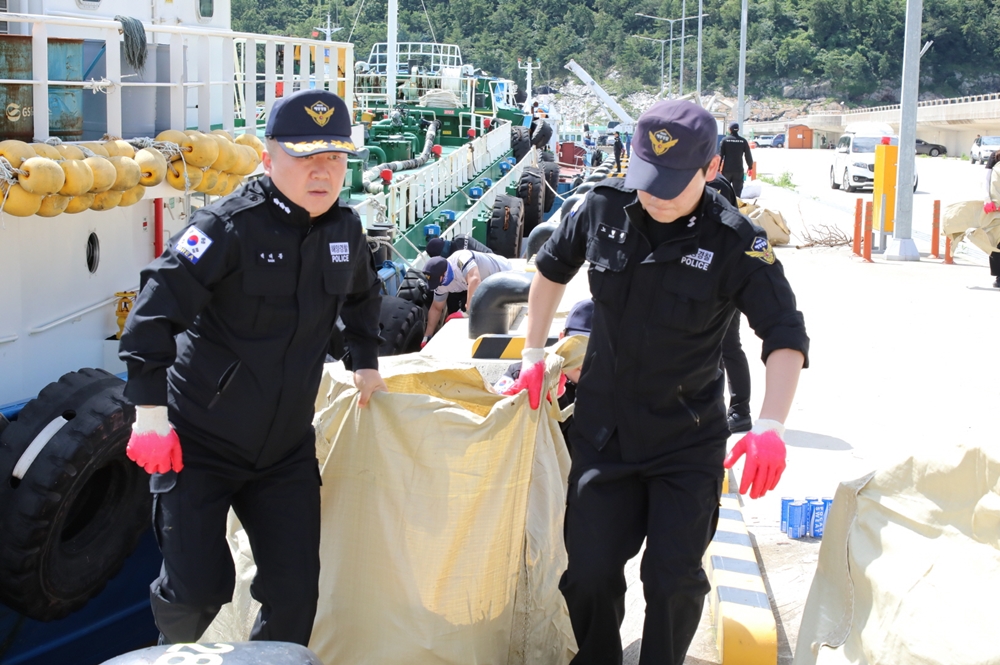 ▲ 해양경찰관이 쓰레기를 육상으로 옮기고 있다.