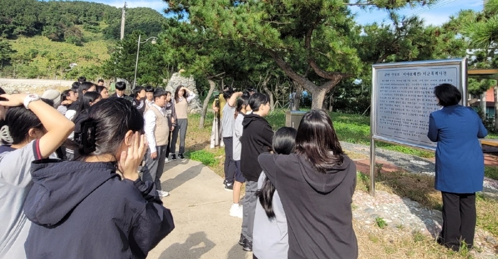 ▲ 안도 이야포 미군폭격사건 설명이 적힌 표지판 앞에 선 학생들. 박성미 시의원이 이야포 미군폭격사건에 대해 설명하고 있다.