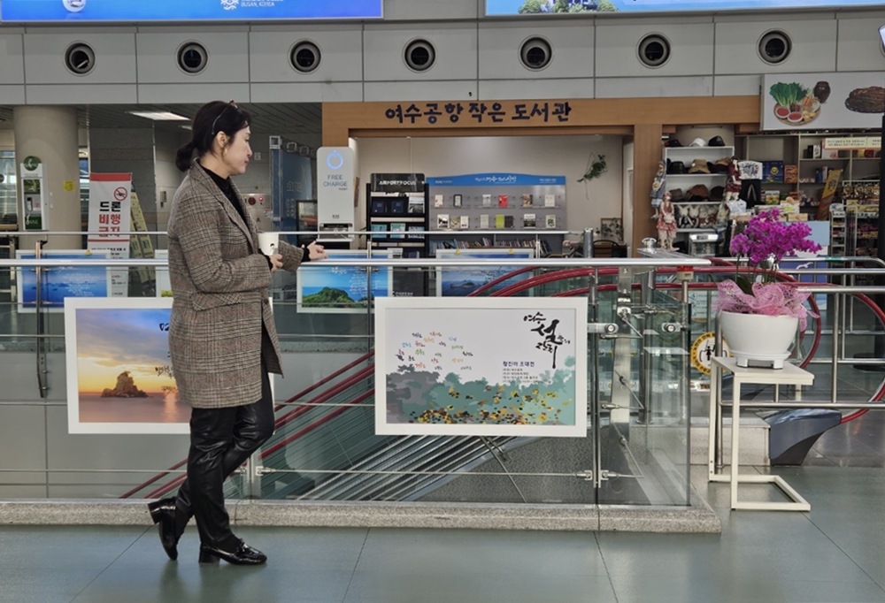 ▲ 황진아 작가가 작품 포스터가 담긴 액자를 바라보고 있다.