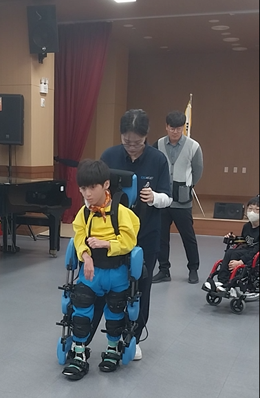▲ 경직으로 서기와 걷기가 어려운 뇌성마비 아동이 웨어러블 로봇을 착용하여 걷기 훈련을 하고 있다.