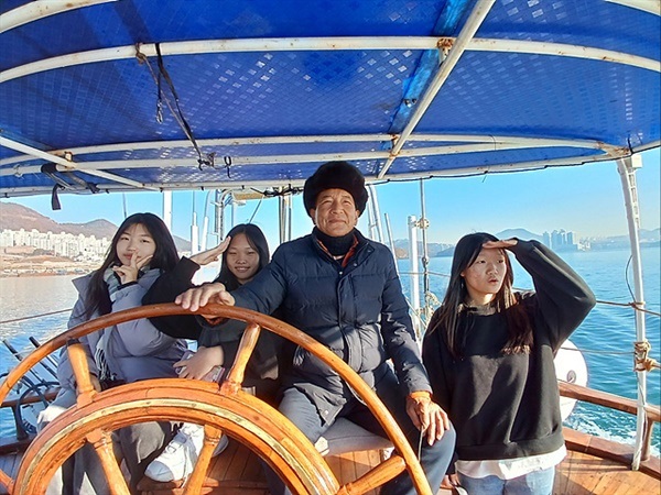 ▲  코리아나호 정채호 선장 옆에서 배 운전하는 걸 지켜보던 학생들이 기념촬영했다. 여수지역의 여러 학교에서 코리아나호를 이용해 해상 현장학습을 하고 있다.ⓒ 오문수