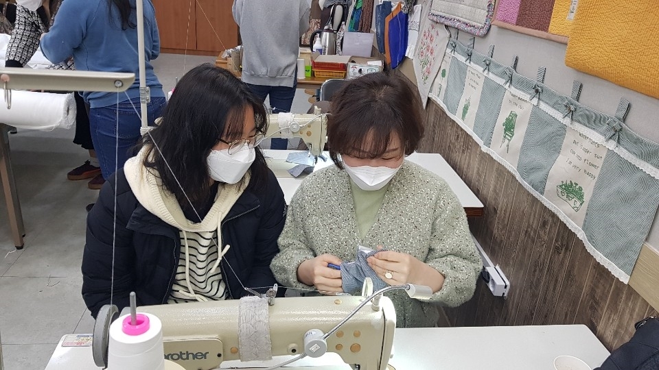 모녀. 엄마가 딸에게 재봉틀사용법을 설명하고 있다, (자료사진)