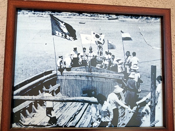 ▲   오마도 개척단기가 걸려있는 작업선에서 바다에 돌을 메워가는 인부들 모습  ⓒ 오문수 