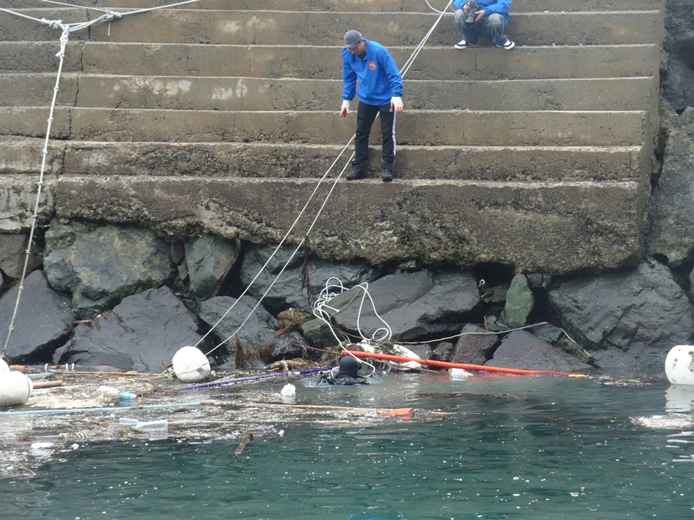 ▲ 잠수부가 수거한 쓰레기를 들어올리기 위해 뭍에서 기다리고 있다.