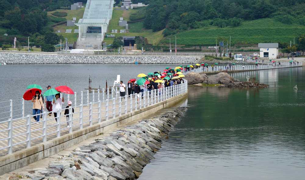 ▲ 시민과 관광객들이 여수시가 제공한 우산을 쓰고 장도의 진섬다리를 건너고 있다. 