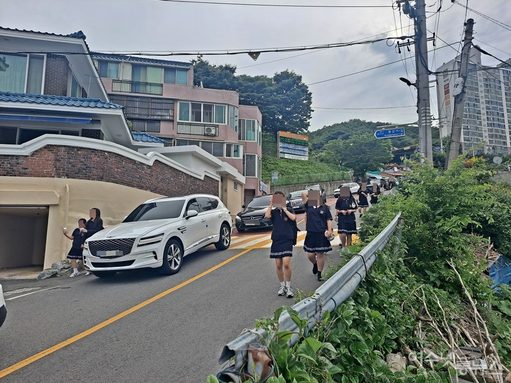 ▲여학생들이 차도를 걷고 있다. 반대편 도로에는 신호를 기다리는 차량이 줄지어 서 있다. ⓒ조찬현
