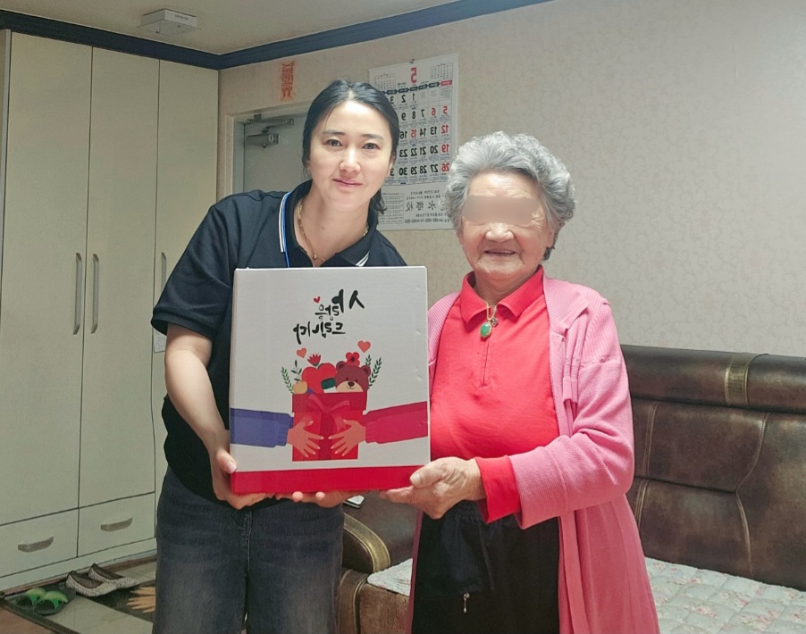 ▲ 어르신이 선물을 받고 기쁜 표정으로 사진을 찍고 있다.