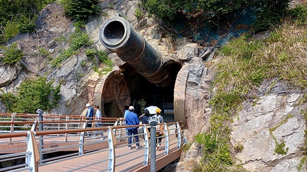 ▲ 가덕도에 있는 대항항포진지 동굴요새 모습. 관광객과 비교하면 포신이 얼마나 큰지 알 수 있다. 1944년말 패전을 앞둔 일본이 미군의 본토 공격에 앞서 한반도에 교두보를 확보할 것이라는 판단하에 오키나와 전투처럼 결사항전하기 위해 파놓은 굴로 강제징용된 조선인들이 팠다고 한다.ⓒ 오문수