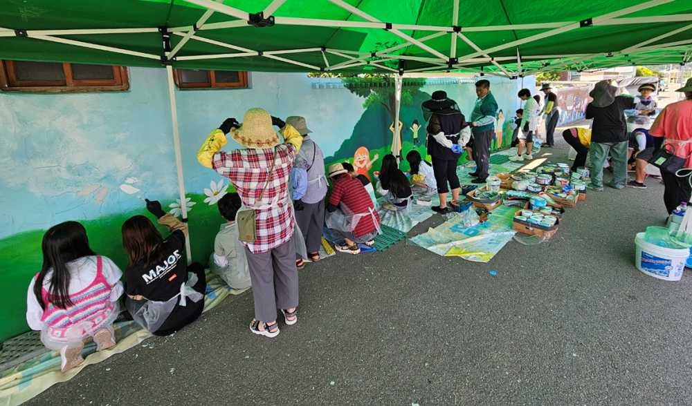 ▲ 율촌면 주민자치위원회와 어린이주민자치회, 주민 등이 여흥 3리 모래목마을에 벽화를 그리고 있다. 