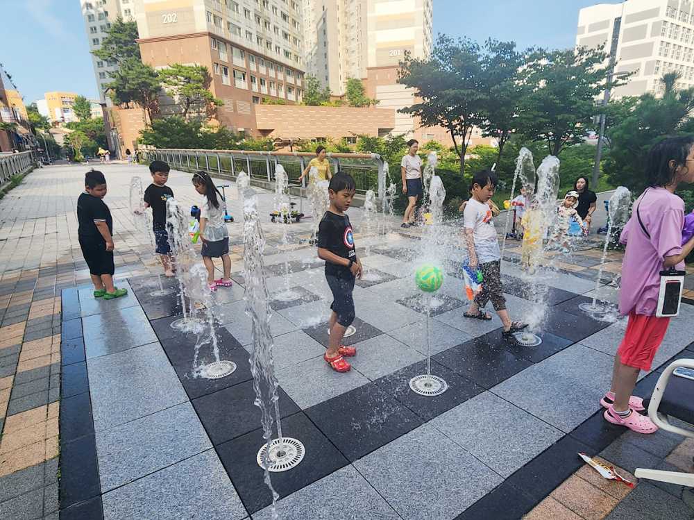 ▲꽃가람공원 내 바닥분수에 20여 명의 아이들이 모여 더위를 피하고 있다.
