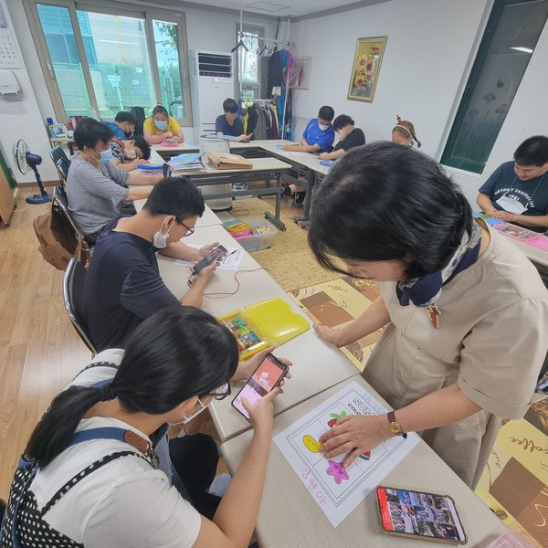▲ 앱에 글씨를 써넣는 단계에서  개인지도 하고 있는  스마트폰 봉사자 선생님 ⓒ 김연우