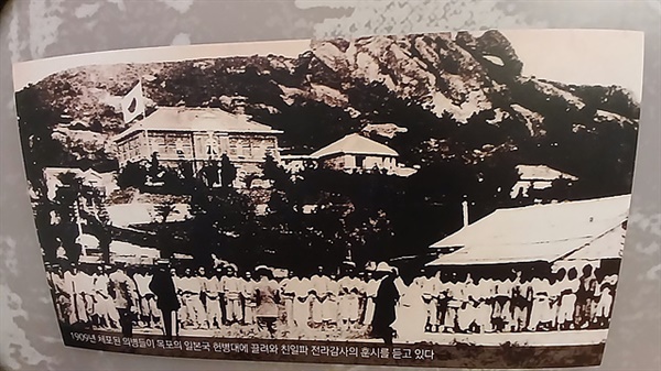 ▲ 1909년 체포된 의병들이 목포의 일본국 헌병대에 끌려와 친일파 전라감사의 훈시를 듣고 있는 사진으로 뒤에일장기가 걸린 일본영사관 건물이 보인다. ⓒ 오문수