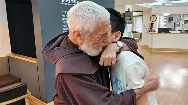 ▲복도에서 만난 장애인 소년을 끌어안아 주는 유의배 신부 ⓒ 오문수