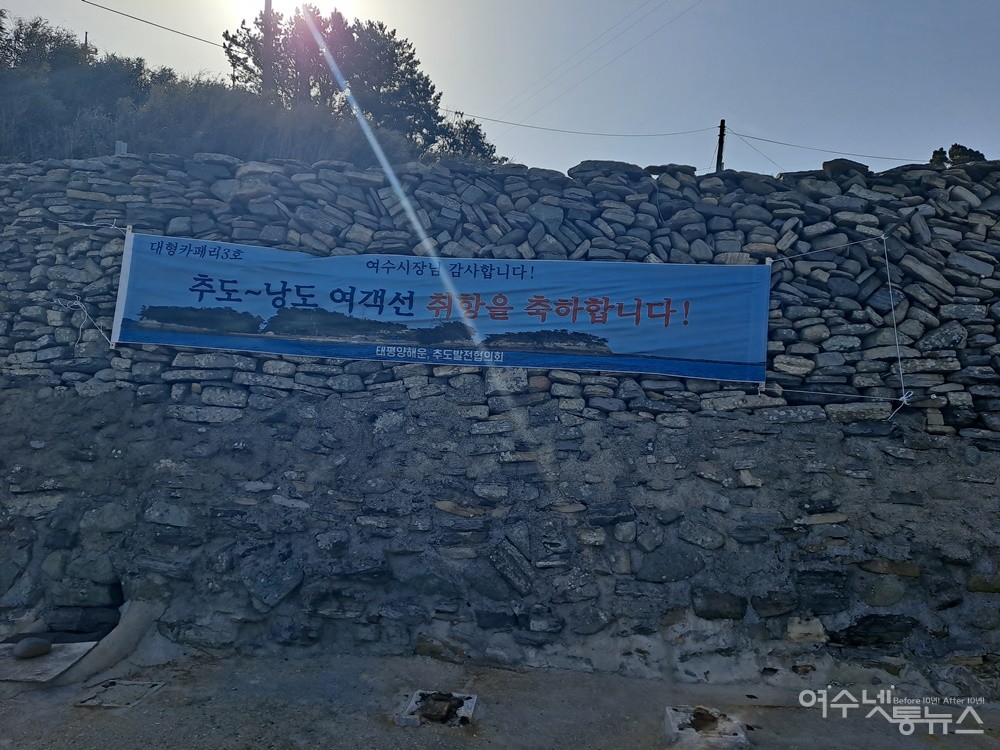 ▲추도-낭도 간 대형카페리3호 여객선 취항 축하 현수막이 돌담에 걸려있다.  ⓒ조찬현