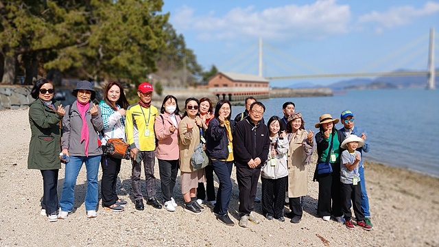 ▲뒤에 보이는 식량창고를 배경으로 남생리 백사장에서 기념촬영한 탐방객들 ⓒ오문수