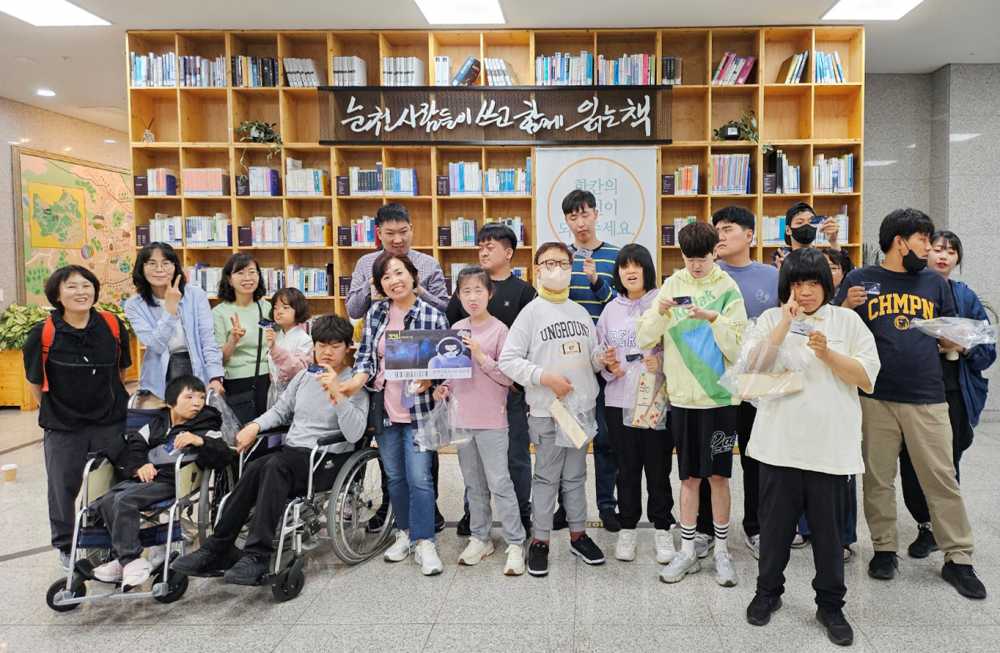 ▲발급받은 도서관회원증을 들고 있 는발달장애인과 보조활동교사 ⓒ순천시