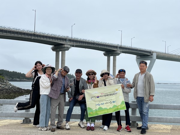 ▲ 완도 보길도의 아름다운 풍경을 배경으로 장애인 3가정과 단체사진을 촬영하고 있다.