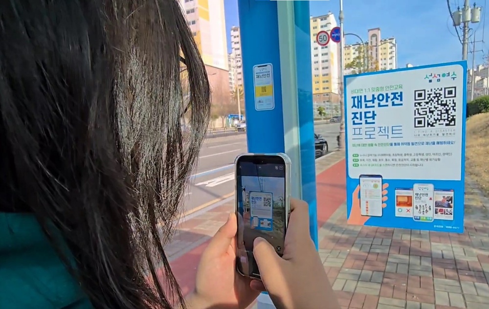 ▲한 여수시민이 버스정류장에 부착된 QR코드를 통해 ‘재난안전 인식도 진단’을 하고 있다. ⓒ여수시