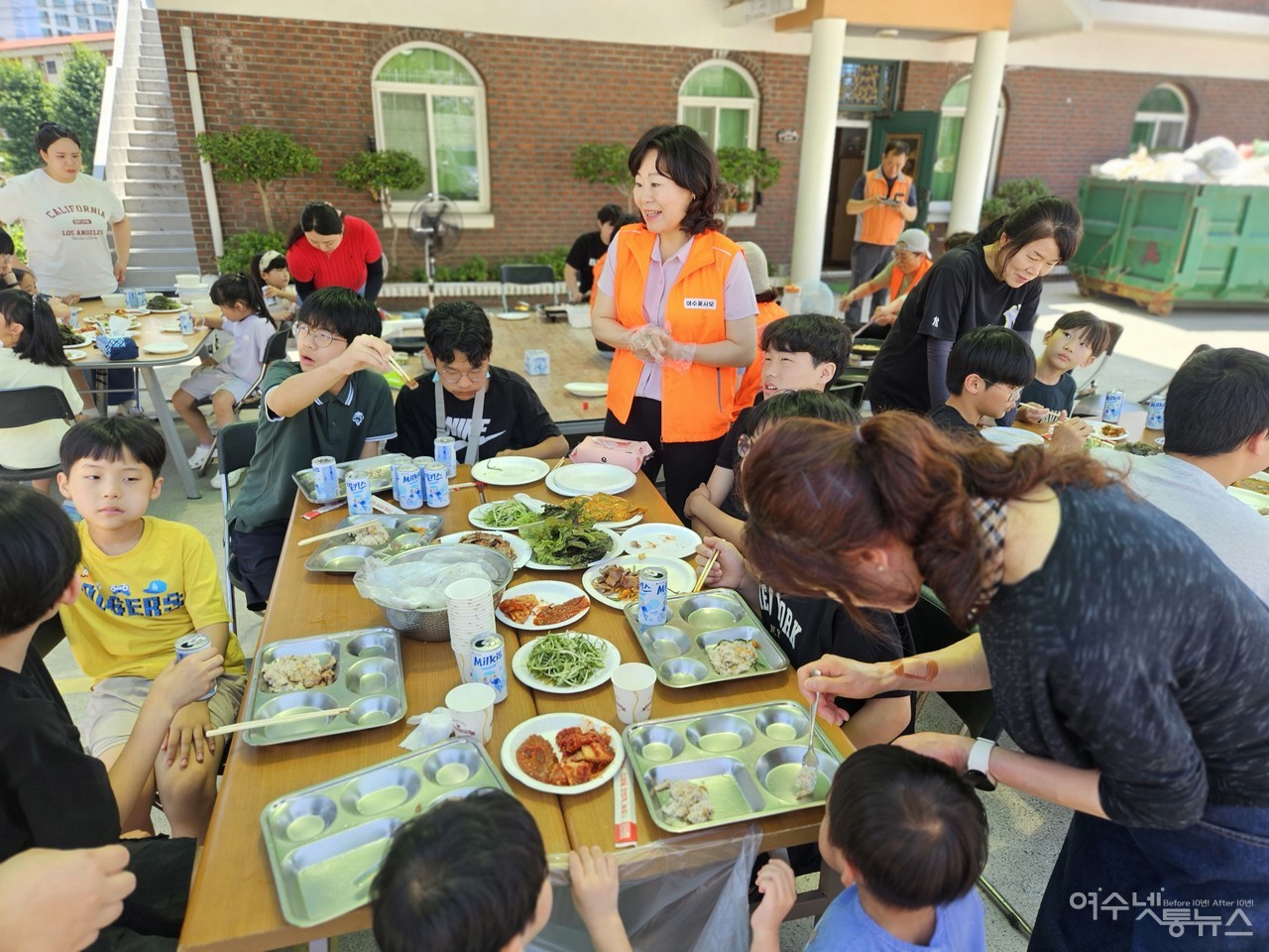 ▲ 아이꿈터 아이들과 함께하는 맛있는 삼겹살 파티중 인사하는 정신출 의원과 김혜경 원장이 아이에게 식사를 챙기고 있다 ⓒ최은서
