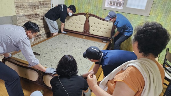 ▲ 습기가 많아 곰팡이핀 벽지 교체를 위해 봉사자들이 무거운 침대를 옮기는 장면