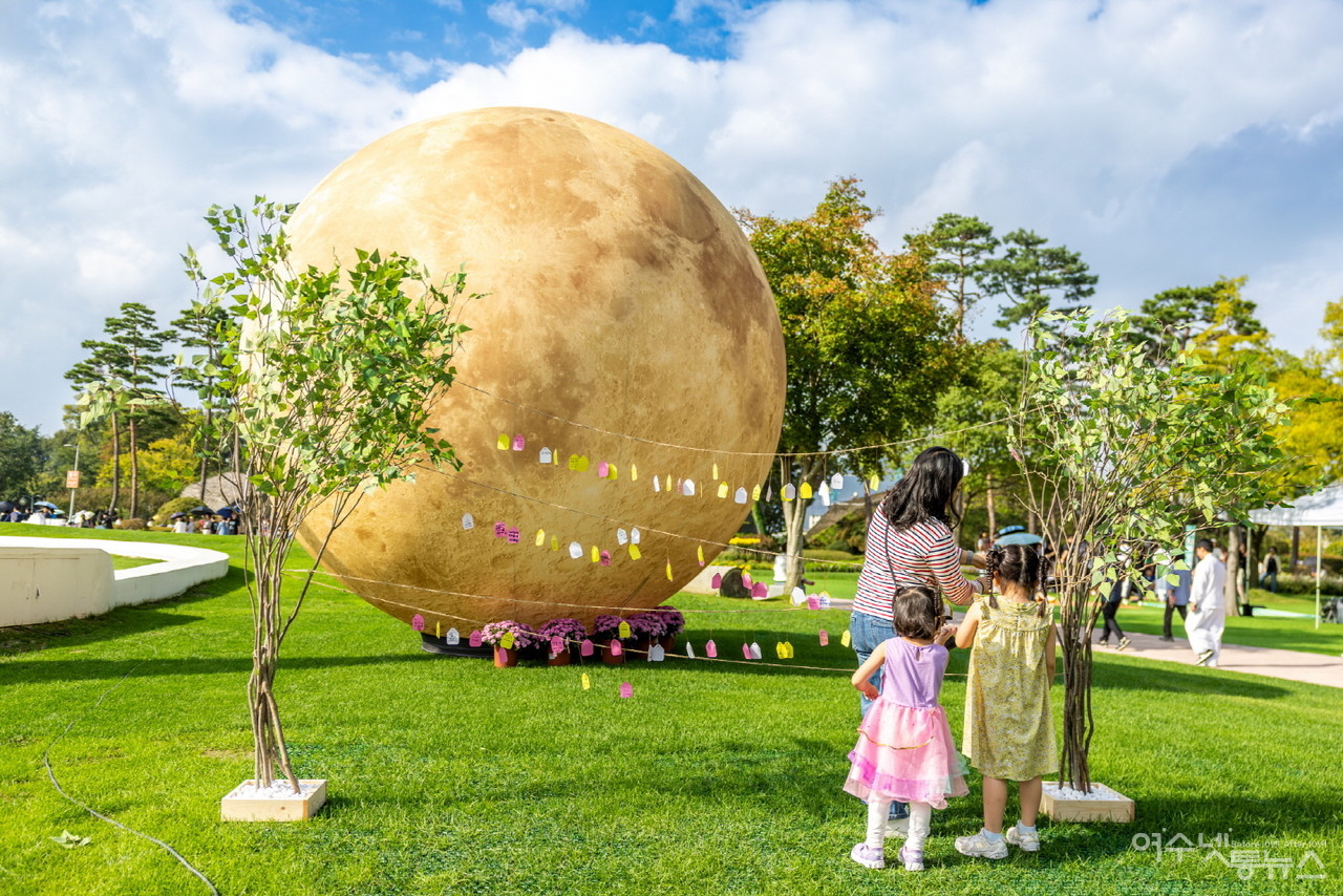 ▲ 순천만국가정원 호수정원 공연장에 설치된 대형 보름달 조형물 앞에서 한 가족이 소원 쪽지를 달고 있다. ⓒ