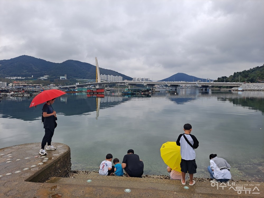 ▲ 바닷가에서 바다생물을 관찰하고 있는 관광객들, 멀리 선소대교가 보인다. ⓒ조찬현