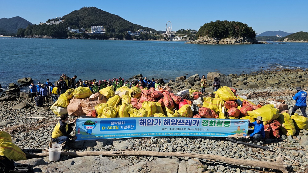 ▲지난 3일 2026여수세계섬박람회 D-300 기념 해양 정화활동에 참여한 시민들이 돌산읍 외치도 해안에서 수거한 해양쓰레기와 함께 기념촬영을 하고 있다. ⓒ여수시